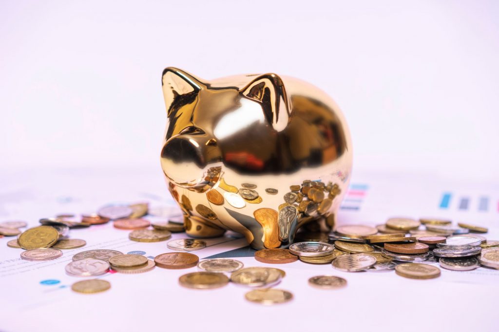 gold and silver coins scattered near gold coin bank